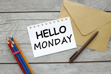 HELLO MONDAY open notepad on wooden table with pencils and envelope