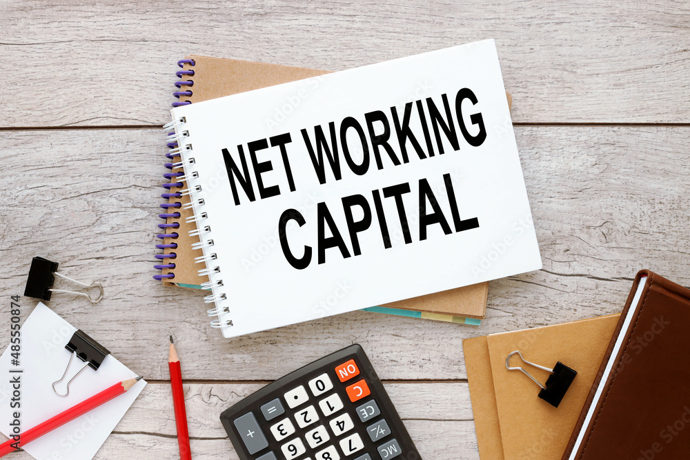 Poster net working capital two notepads with text on a rustic background near a calculator and other suppli