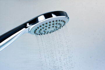 Naklejka na ściany i meble Image of a modern shower head splashing water. Close up background.