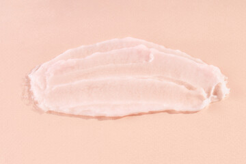 Creamy balm or mask smear on a beige background. Creamy pale pink  texture of hair cosmetics 