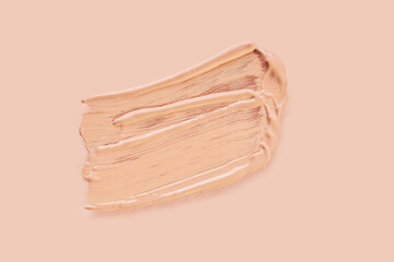 Light beige liquid makeup smear of creamy luminous blusher on beige background.  Cosmetic Liquid Stroke. Skin Tone Cream