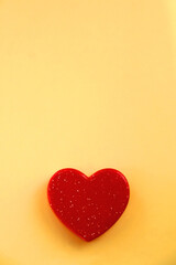 Small red heart on bright yellow background. Love concept. Flat lay.