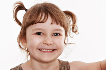 Cheerful positive adorable small child with two pony tails, dressed in striped t shirt, expresses...