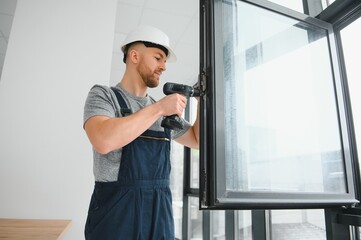 service man installing window with screwdriver