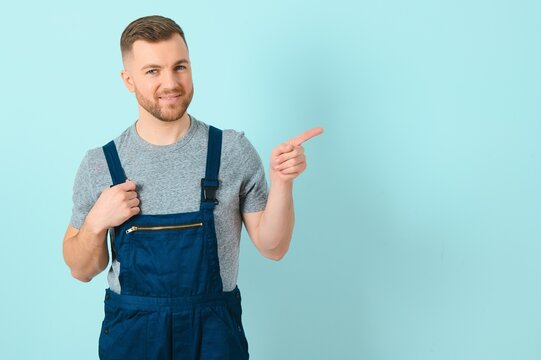 Young electrician man or Craftsmen over isolated blue wall pointing to the side to present a product
