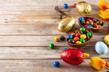 Colorful chocolate Easter eggs on wooden table. Copy space