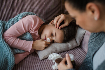 Mother taking care of her sick daughter at home.