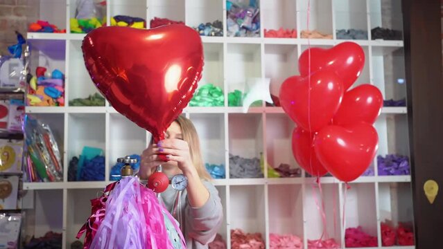 a woman inflates of helium from a foil balloon in the shape of a heart.