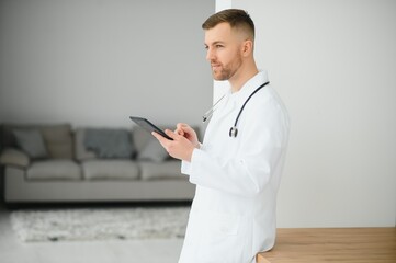 Young male cancer specialist in labcoat using digital tablet at clinic