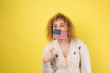 A young happy girl with a smile on her face holds an American flag in her hands. Symbol of patriotism and freedom.