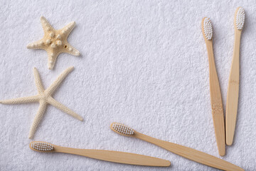 A set of eco-friendly bamboo wooden toothbrushes with starfish on a white towel.
