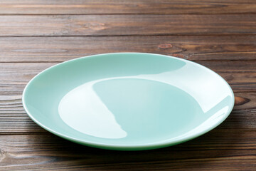 Perspective view of empty blue plate on wooden background. Empty space for your design