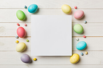 round frame multicolored Easter eggs with white blank paper on a brown background, close-up, space for text, blank for design, selective focus, tinted image