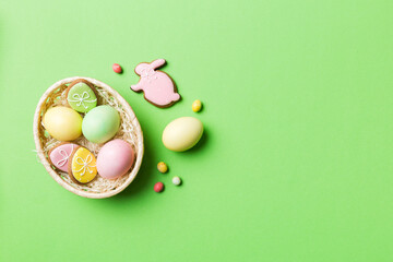 Colorful easter cookies in basket with Multi colors Easter eggs on colored background . Pastel color Easter eggs. holiday concept with copy space