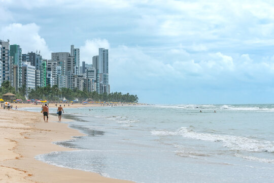 Landscape of a beautiful brazilian beach of the northeast, people walking on the beach, bathers on the water and the city on background. Boa Viagem beach in Recife PE, Brazil.