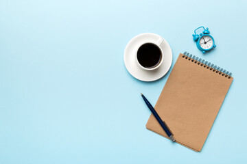 Modern office desk table with notebook and other supplies with cup of coffee. Blank notebook page for you design. Top view, flat lay