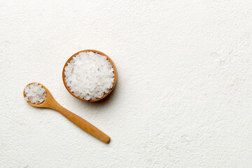 A wooden bowl of salt crystals on a wooden background. Salt in rustic bowls, top view with copy space
