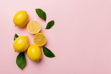 Many fresh ripe lemons with green leaves on colored background, top view, space for text