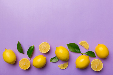 Many fresh ripe lemons with green leaves on colored background, top view, space for text