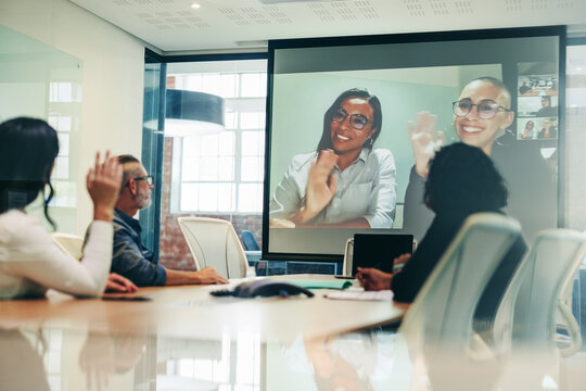 Team of colleagues greeting their business associates during a virtual meeting