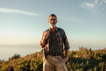 Male hiker smiling at the camera at sunset