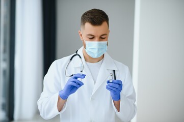 Fototapeta premium A doctor in blue gloves holding a bottle with vaccine. Close up shot. Medicine and healthcare concept