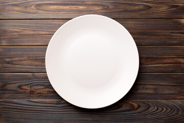 Top view of empty light plate on wooden background. Empty space for your design