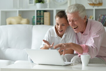 Boy and grandfather with a laptop at home