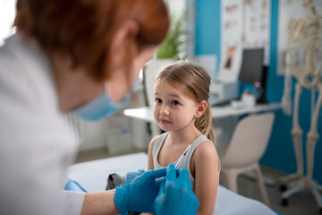 Worried little girl getting vaccinated in doctor's office.