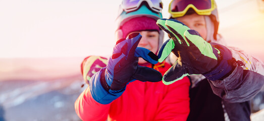 Fototapeta na wymiar Snowboarders man and woman show heart sign with hands, winter travel love banner concept