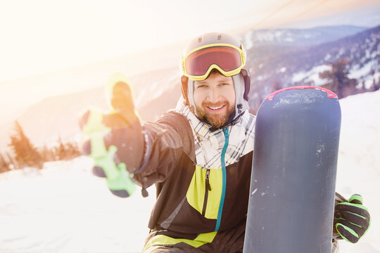 Smile man with snowboard take selfie photo background ski resort sunset. Concept banner winter travel, Sheregesh Kemerovo region Russia