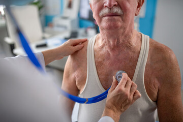 Close-up of unrecognizable senior man being checked by his doctor in doctor's office.