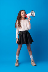 Cute schoolgirl holding megaphone against blue background