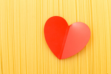 spaghetti yellow background with a red heart close. raw pasta macro