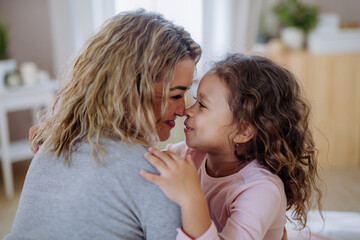 Close-up of happy mother with her little daughter hugging and looking at each other at home. - obrazy, fototapety, plakaty
