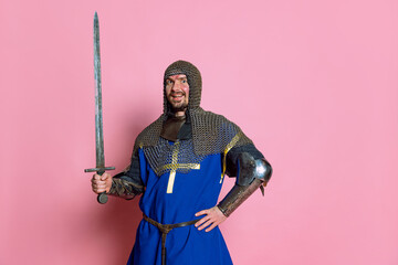 Half-length portrait of man, medieval warrior or knight with wounded face posing isolated over pink...