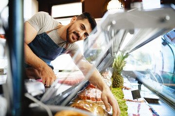 Portrait of confident young salesman standing in butcher's shop