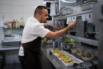 Chef taking order slip in commercial kitchen.