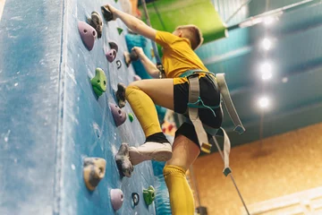 Fotobehang Teenage boy at indoor climbing wall. Kid having fun at bouldering wall. Child learning at climbing class. Sports healthy lifestyle. Youth at climbing summer camp © matimix