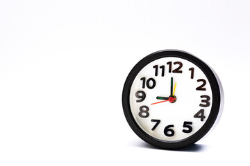 Black alarm clock isolated on white background. The clock set at 9 o'clock.