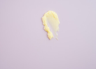 Cosmetic products creamy yellow stain texture on pink background. Texture of natural cosmetics,...