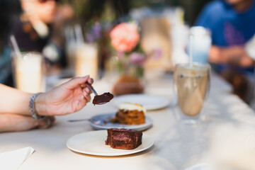 Handwith spoon eating delicious chocolate cake in cafe.