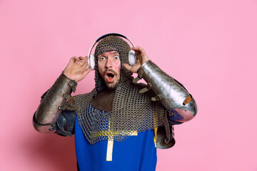 Half-length portrait of man, medieval warrior or knight listening to music in headphones with...
