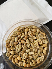 Raw green coffee beans in bowl. White pack with copy space