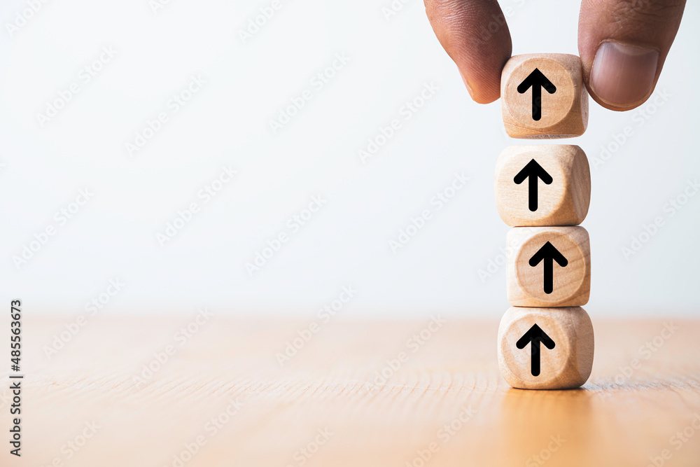 Poster Hand putting up or increasing arrow which print screen on wooden cube block for dividend benefit growth and enhance investment concept.