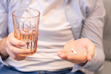Close up man drinking white pills cold season virus allergy