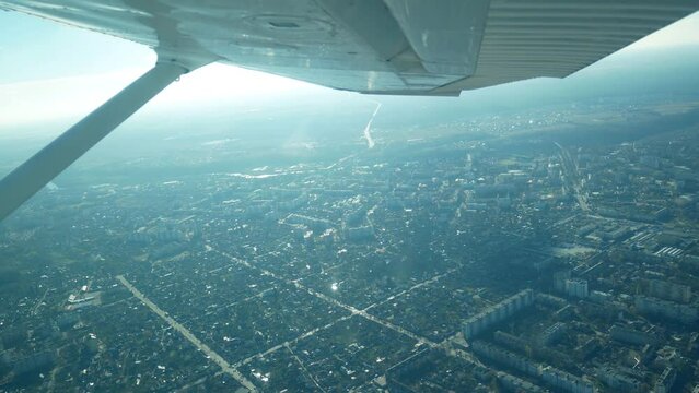 Flying in a small light plane. Aerial view from the window of a small aircraft airplane in flight over the city 