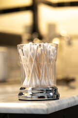 White Cotton Swabs in a Glass Container on the Edge of a Bathroom Vanity