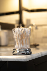 White Cotton Swabs in a Glass Container on the Edge of a Bathroom Vanity