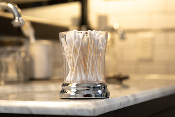 White Cotton Swabs in a Glass Container on the Edge of a Bathroom Vanity